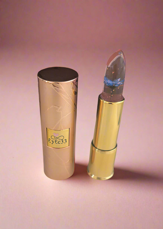 Lipstick with a gold cap on a pink background